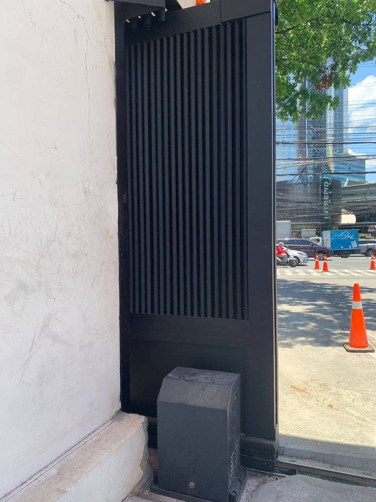 Black slatted telescopic sliding gate with its heavy-duty motor housing